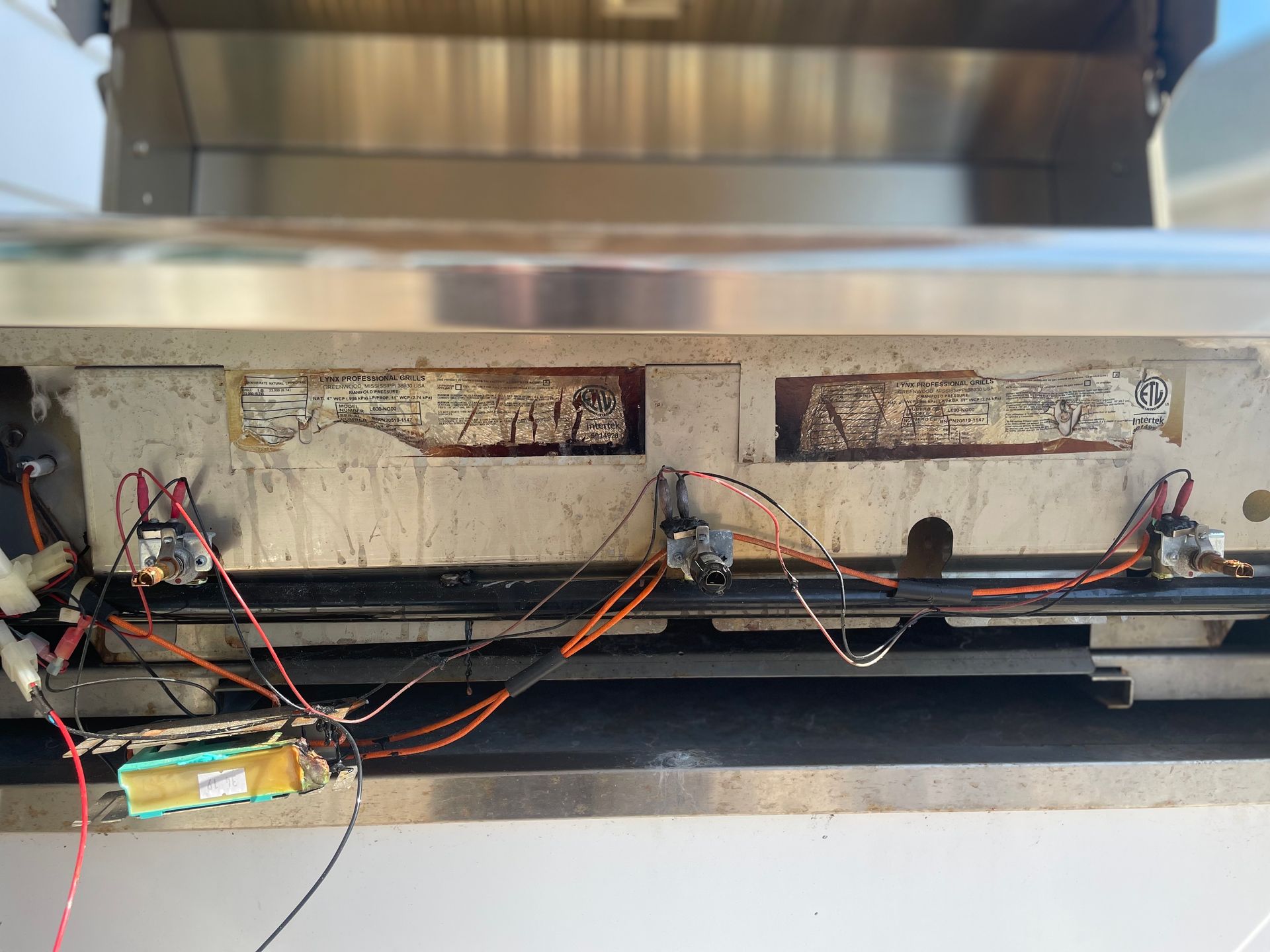 Close-up of the underside of a grill showing electrical components and controls wired together.