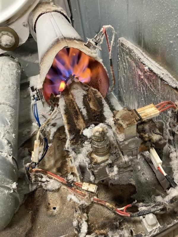 Burning gas dryer components with charred wiring, covered in frost.