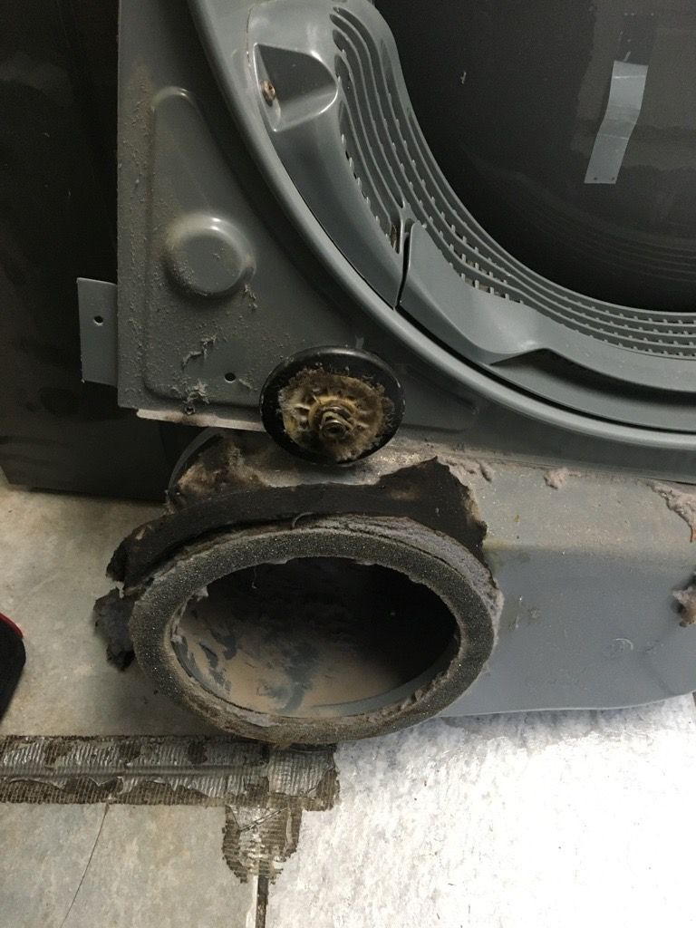 Close-up of a dryer's interior vent; black rubber collar damaged.