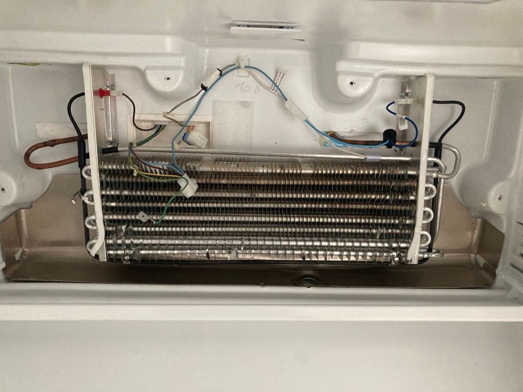 Inside of a refrigerator freezer compartment showing a coil system with wires and tubing.
