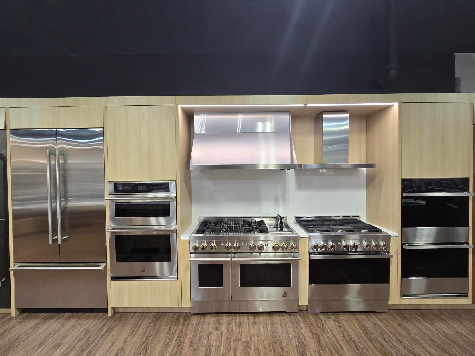 Kitchen appliances: stainless steel refrigerator, ovens, cooktops, and range hood display.