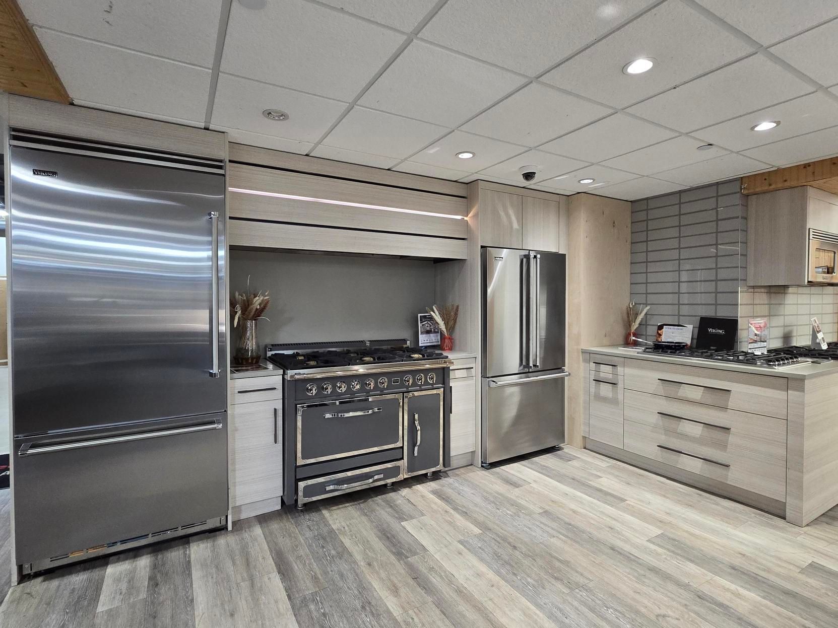 Modern kitchen with stainless steel appliances and light wood cabinets, gray range.