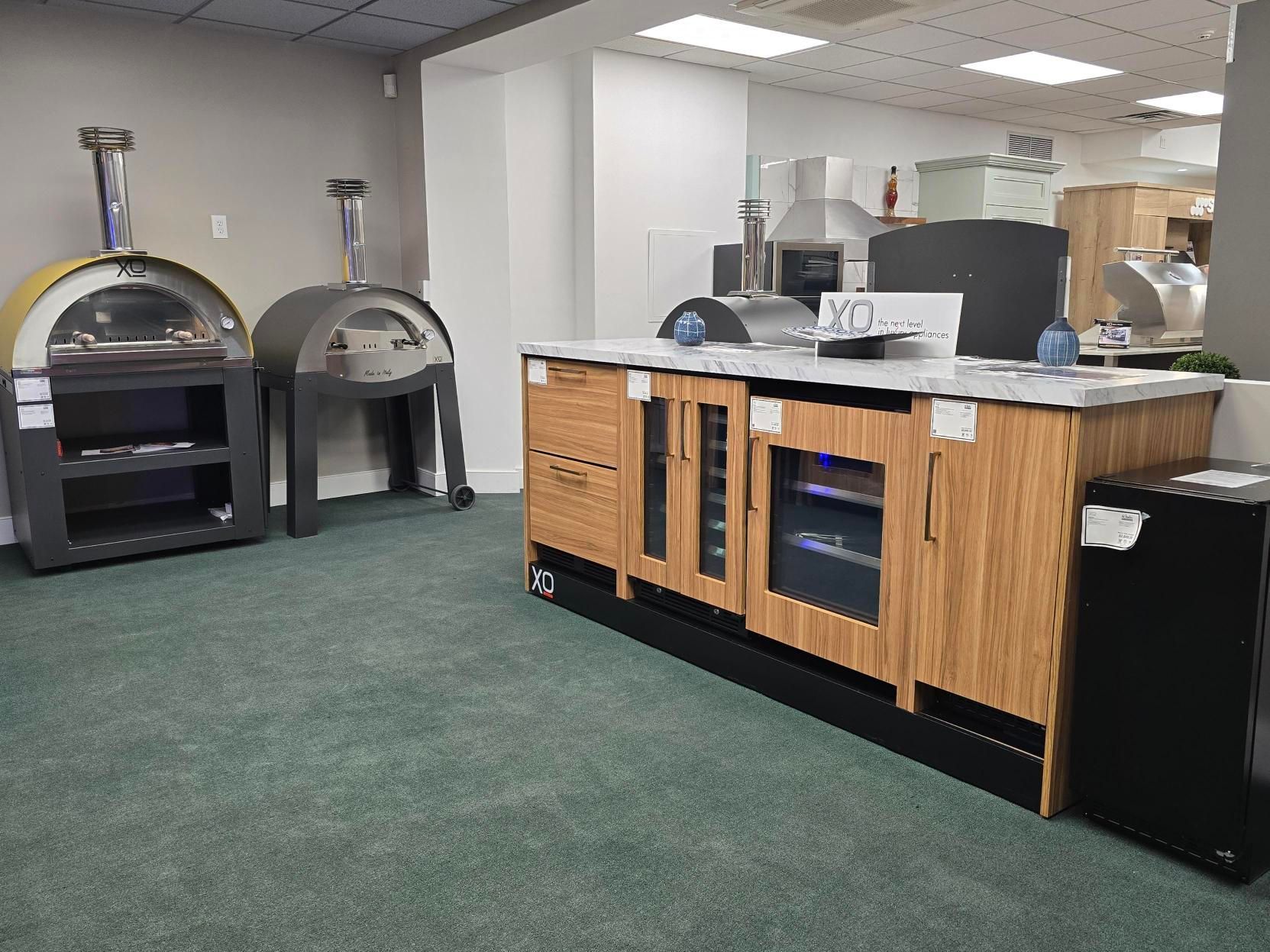 Indoor showroom with pizza ovens and a wooden bar with a refrigerator.