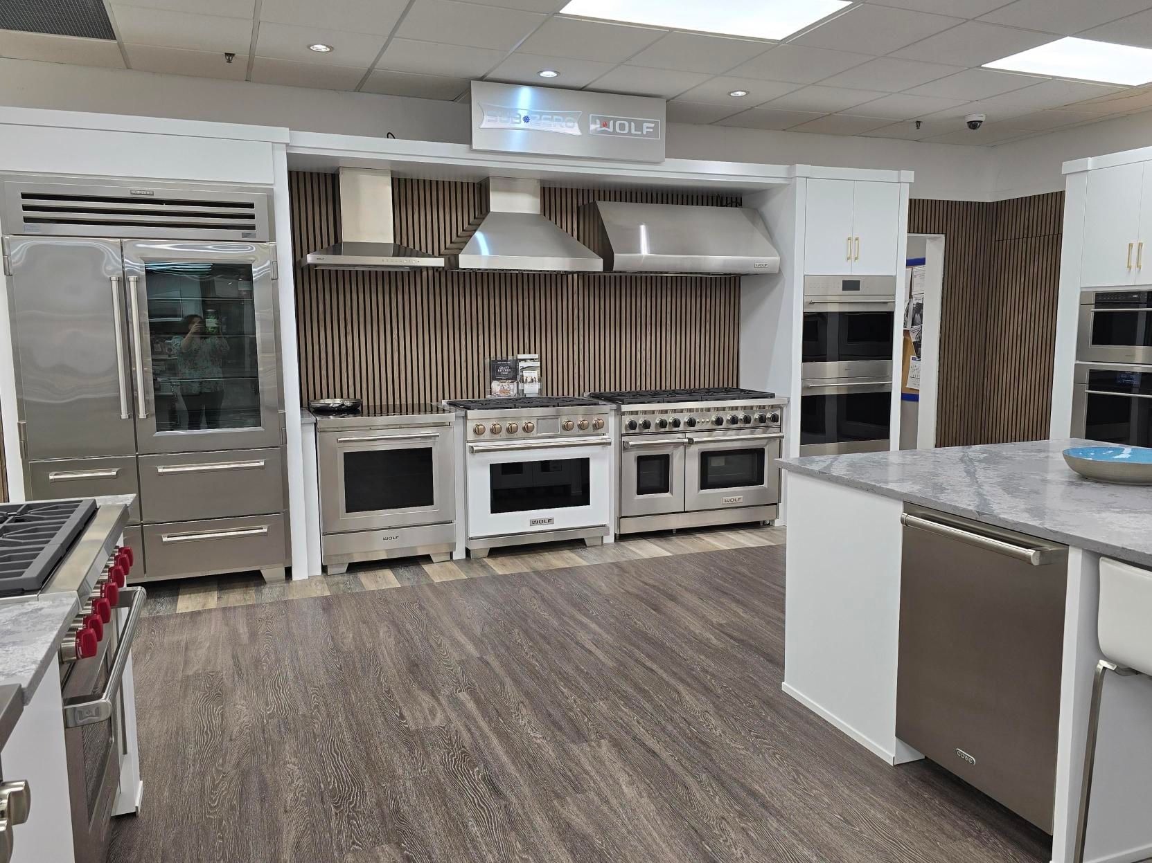 Kitchen appliance showroom display with stainless steel refrigerators, ranges, and ovens.