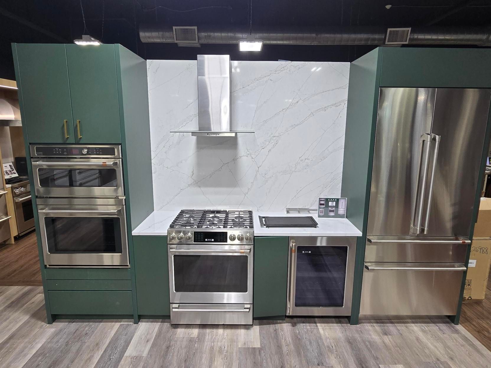 Green kitchen cabinets with stainless steel appliances.