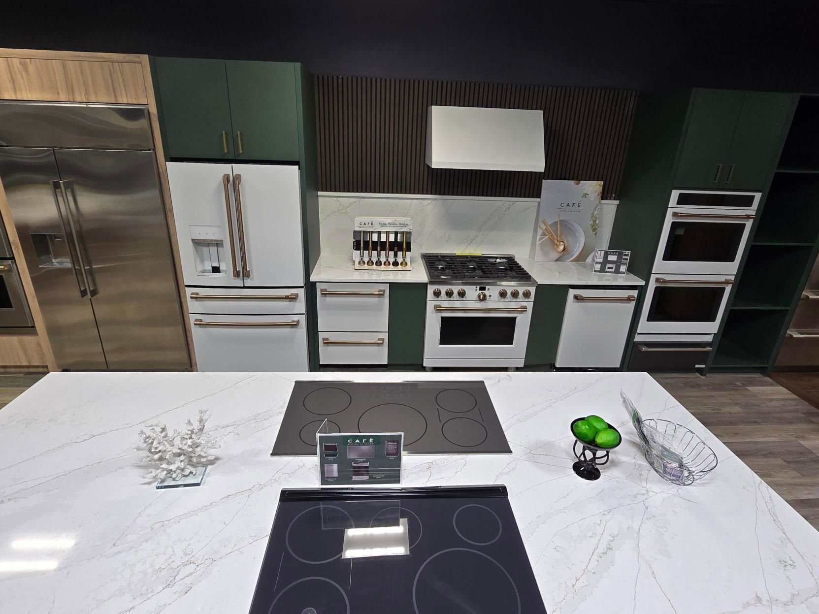 Kitchen with white appliances, dark green cabinets, and a white countertop island.