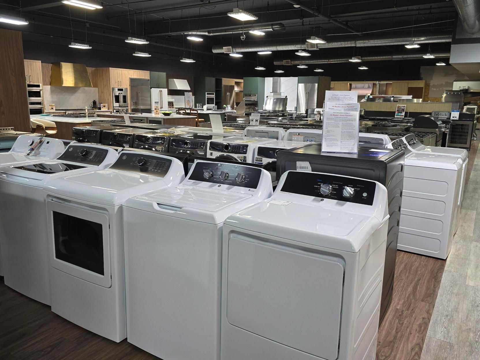 A large appliance store displays rows of white washing machines and dryers; other kitchen appliances are in the background.