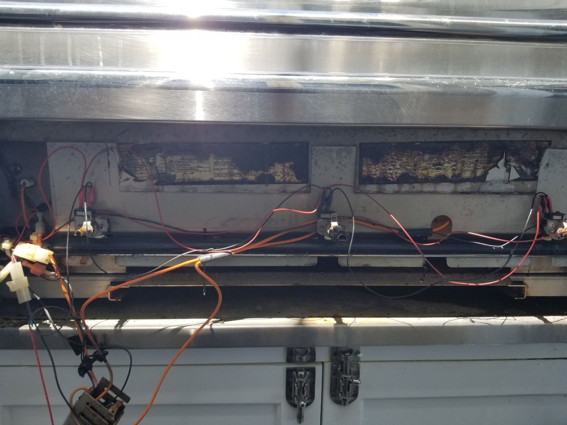 Wiring and components within a metal compartment, including orange wires and electrical devices.