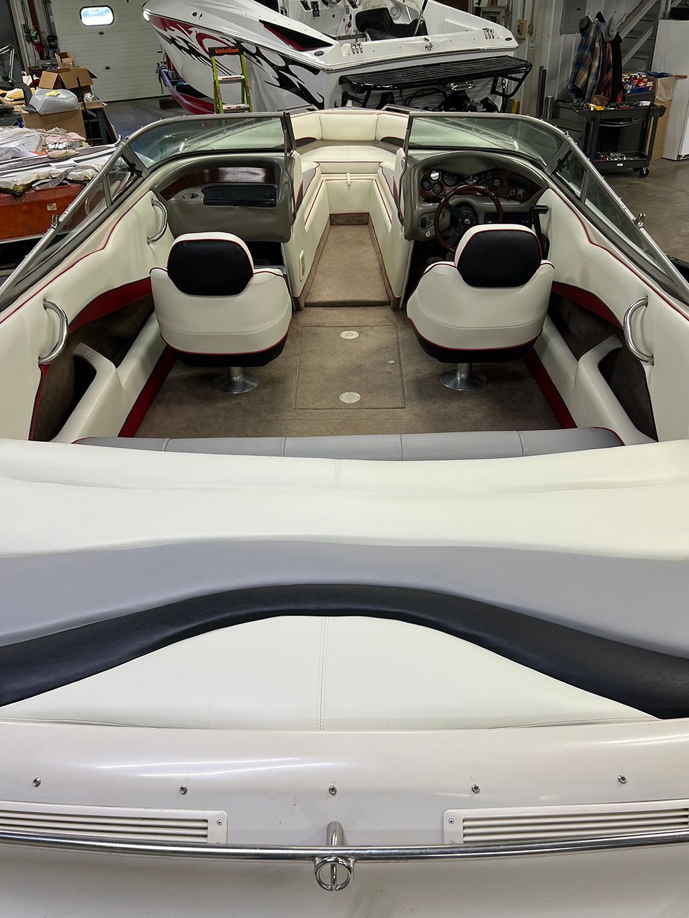Interior of a white speedboat with two black bucket seats, steering wheel, and a rear bench seat.