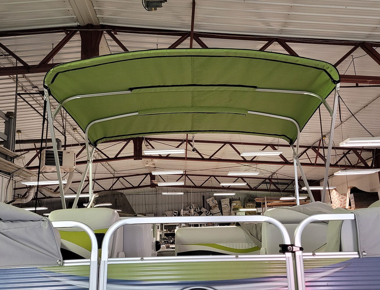 Pontoon boat with green canopy in a garage.