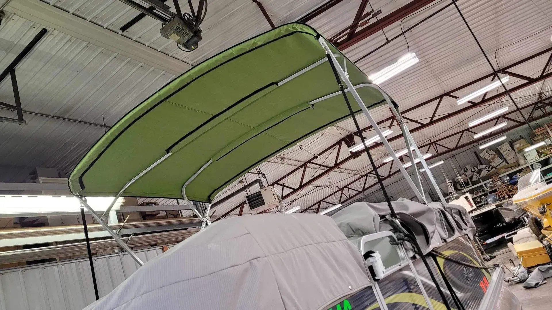 Green boat canopy over a covered boat in a warehouse.