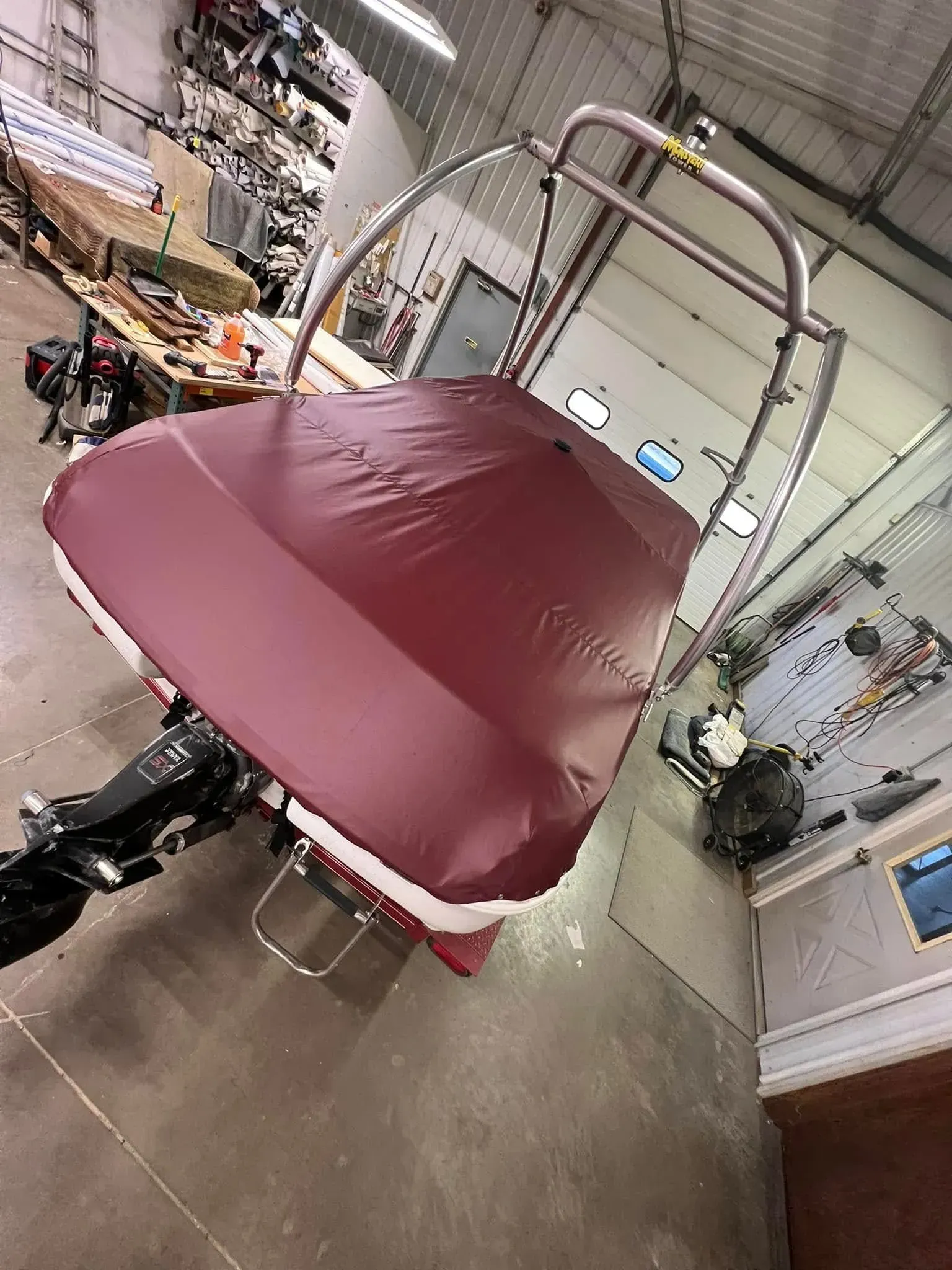 Maroon boat cover on a boat frame, outdoors or in a garage.