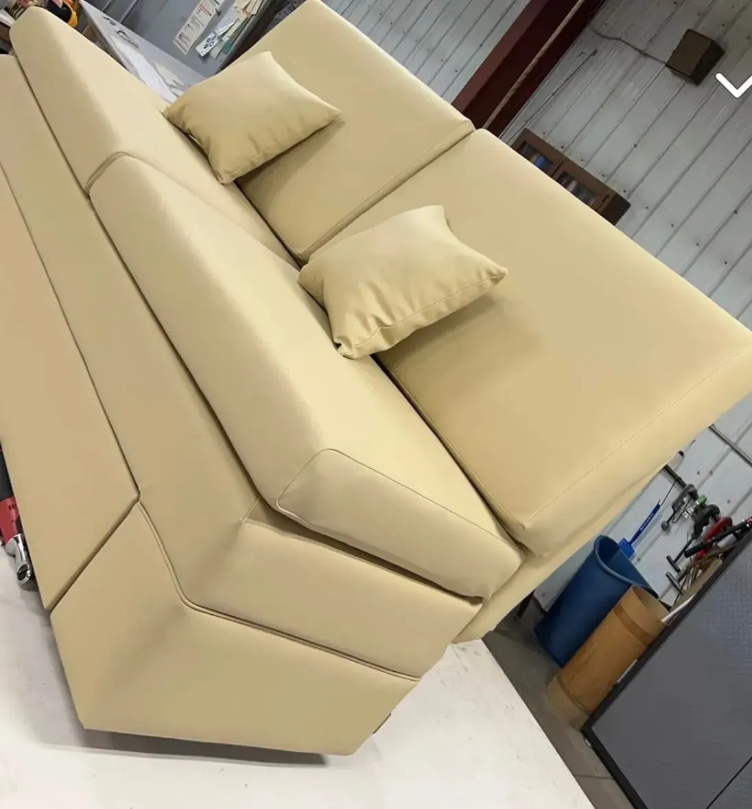 Tan sectional sofa with two throw pillows in an industrial setting.