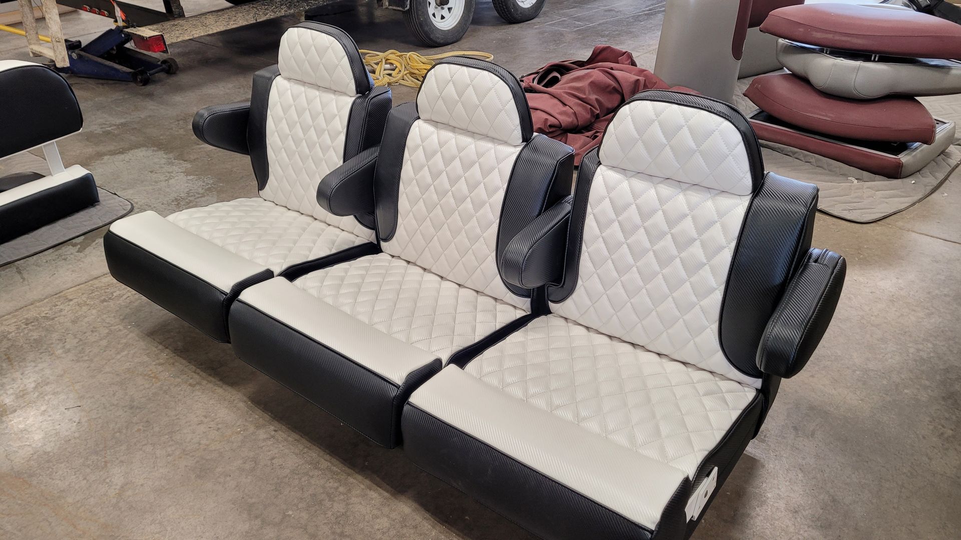 Three-seat bench with black and white diamond-stitched upholstery, armrests, in a workshop setting.