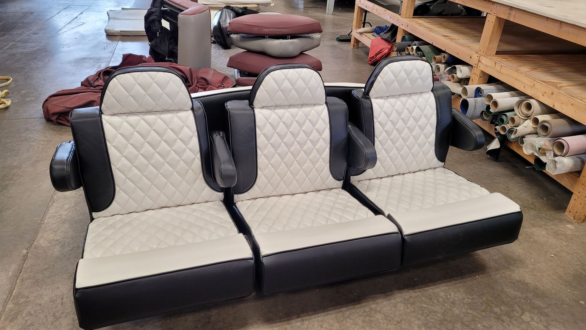 Three-seat black and white upholstered bench with diamond stitching, in a workshop setting.