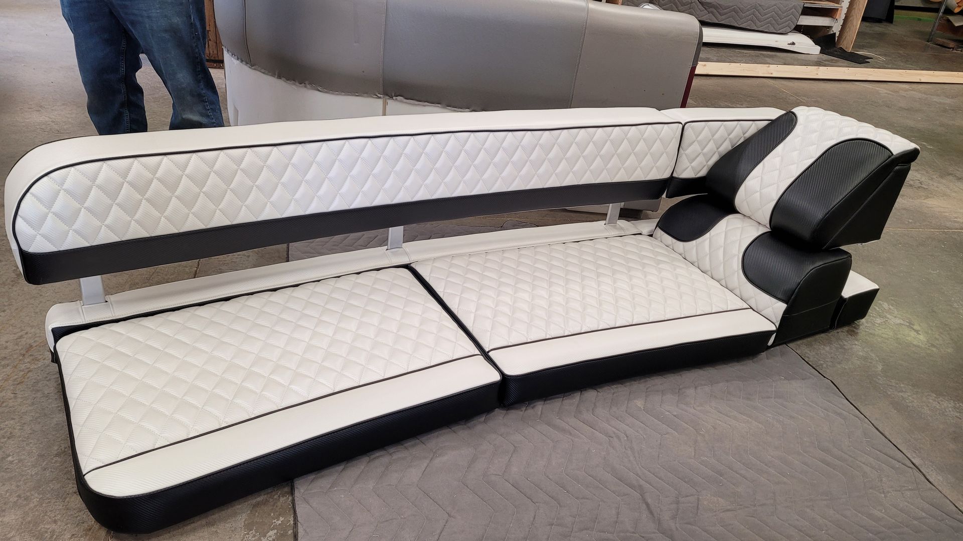 White and black upholstered boat seating; curved design with quilted pattern.