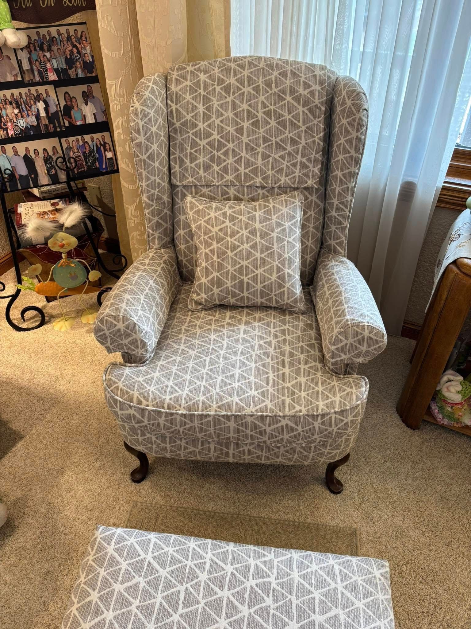 Wingback chair and footstool with grey geometric pattern in room with light carpet.