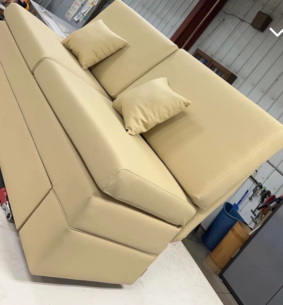 Beige sectional sofa with two matching pillows, in a workshop setting.