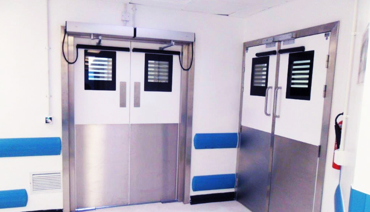 A hospital hallway with stainless steel doors and blue and white walls