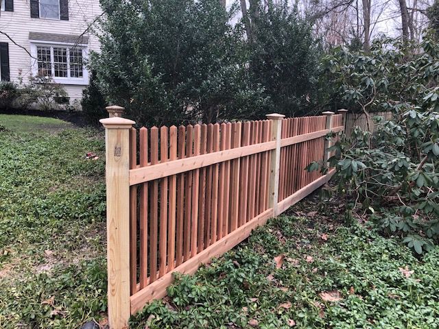 Wooden picket fence with decorative posts in a yard.