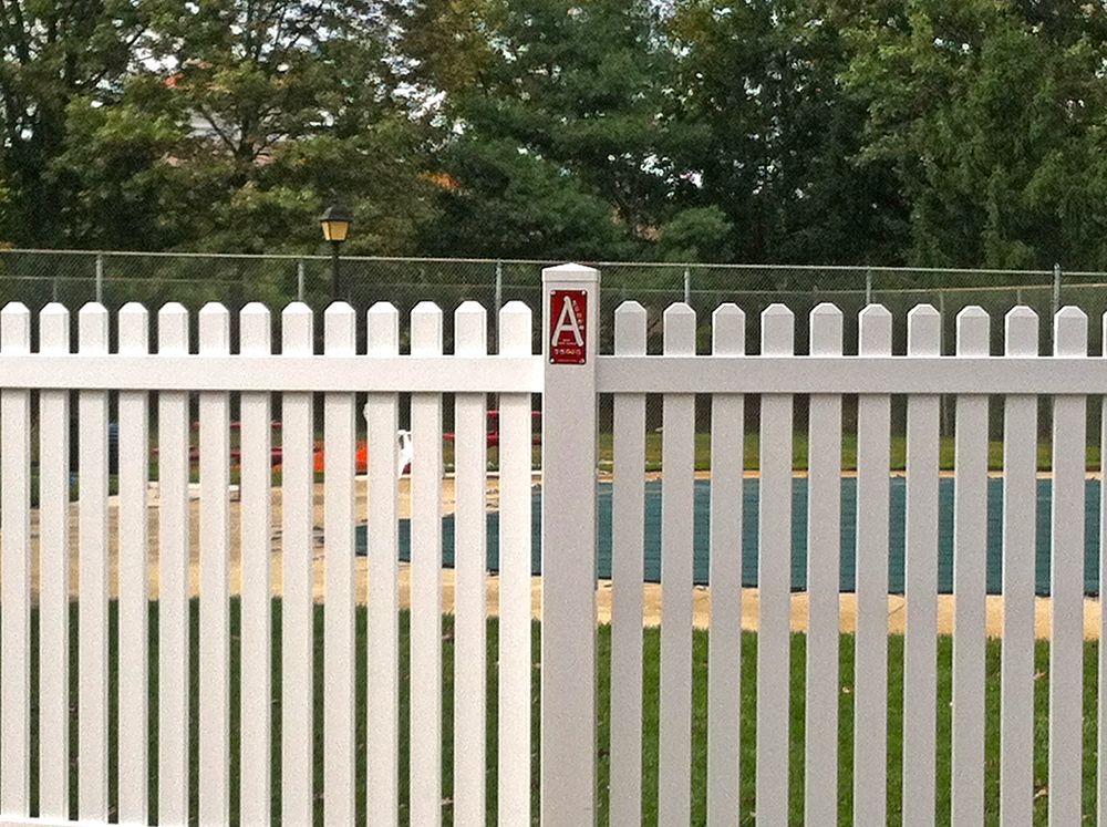 White picket fence surrounding a pool, with a red 