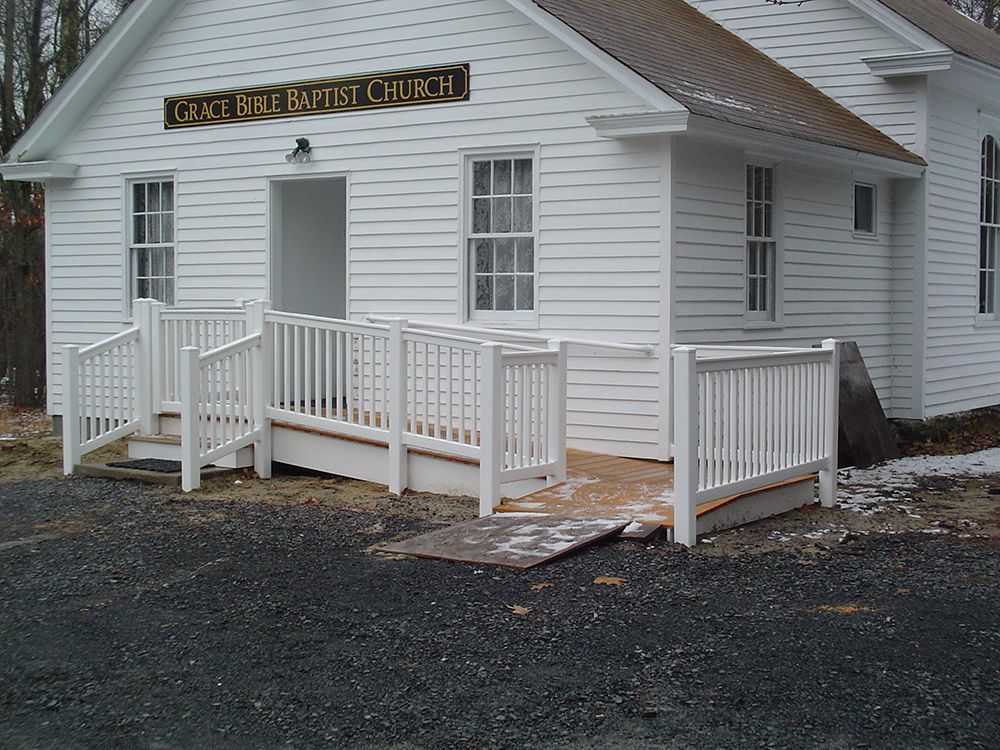 White church building with a ramp and railing for accessibility.