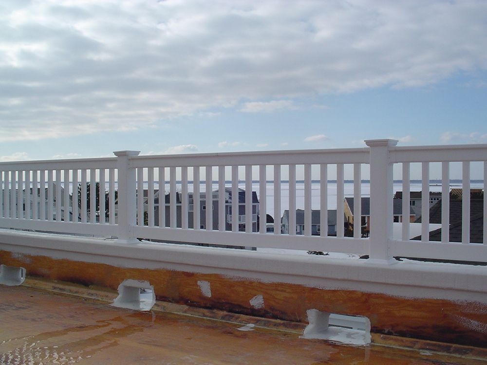 White picket fence along a waterfront, against a cloudy sky.