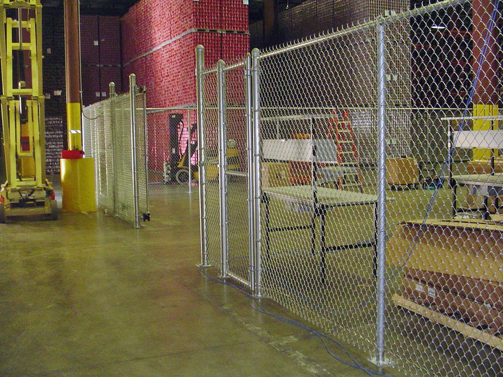 Chain link fence inside warehouse, with a forklift on the left.