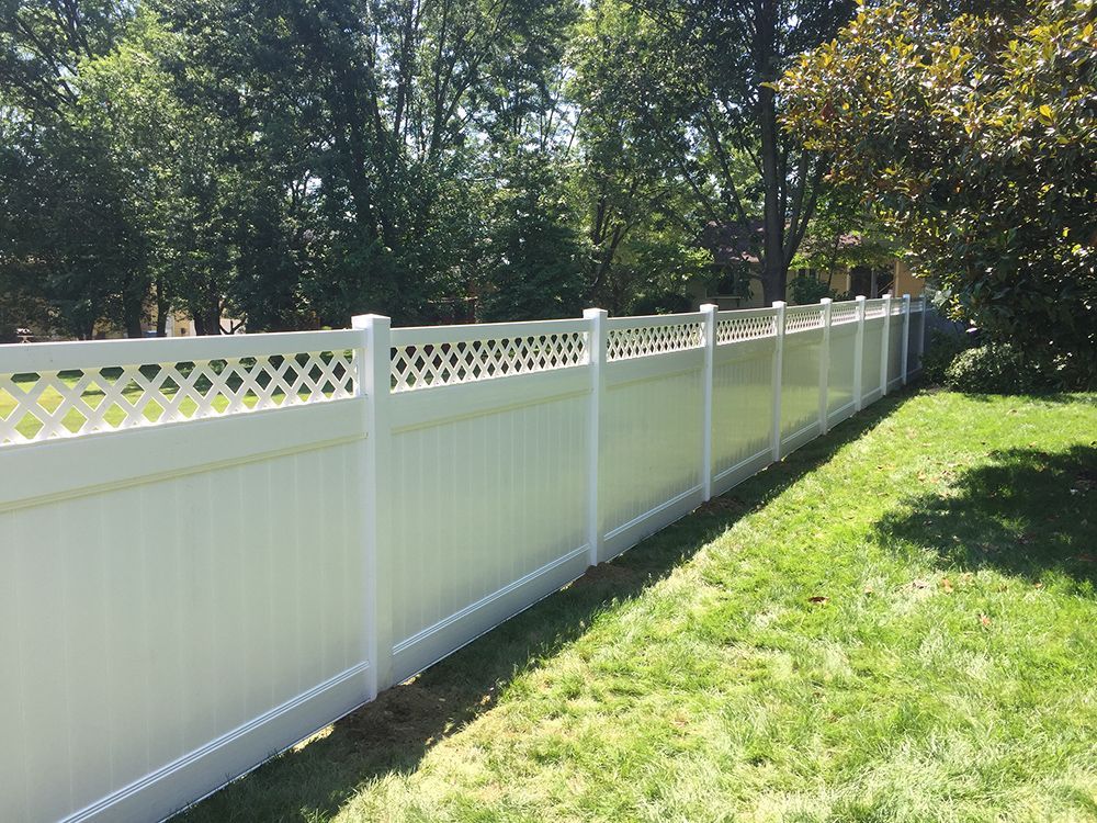 White vinyl fence with lattice top in a grassy backyard.