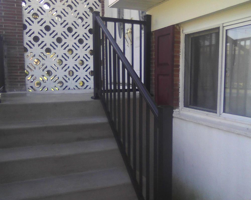 Exterior concrete stairs with black railing leading to a building entrance.