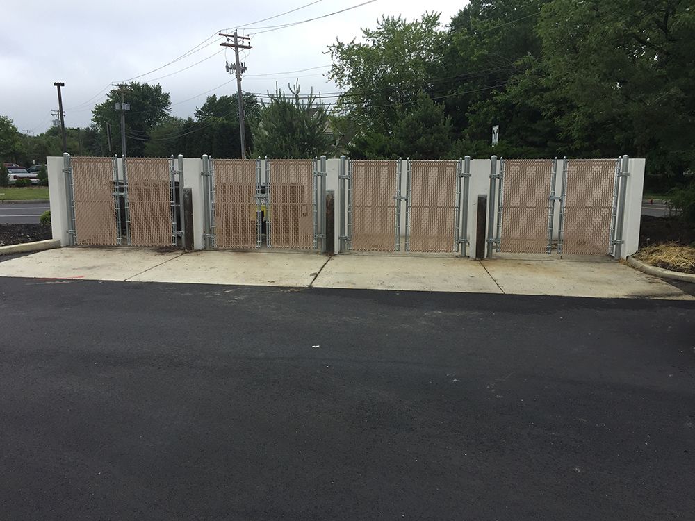 Dumpster enclosure with six gated sections and a concrete pad.