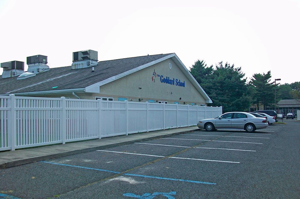 A school building with a white fence and a parking lot.