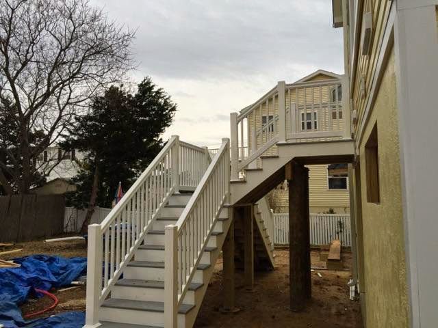 Exterior staircase leading up to a deck attached to a house; cloudy sky.