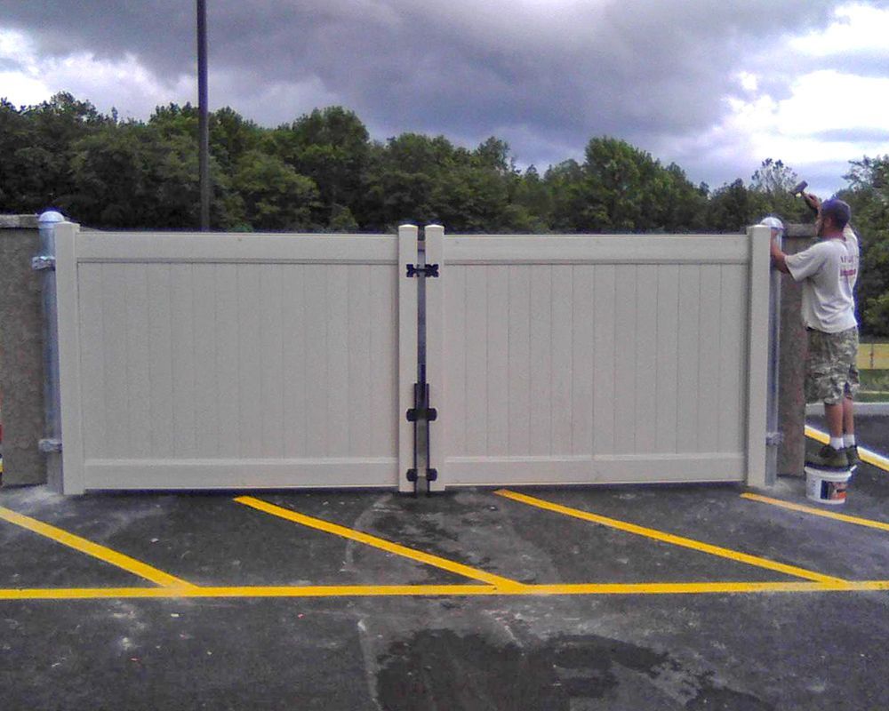 Tan fence with a person working, set in a parking lot.