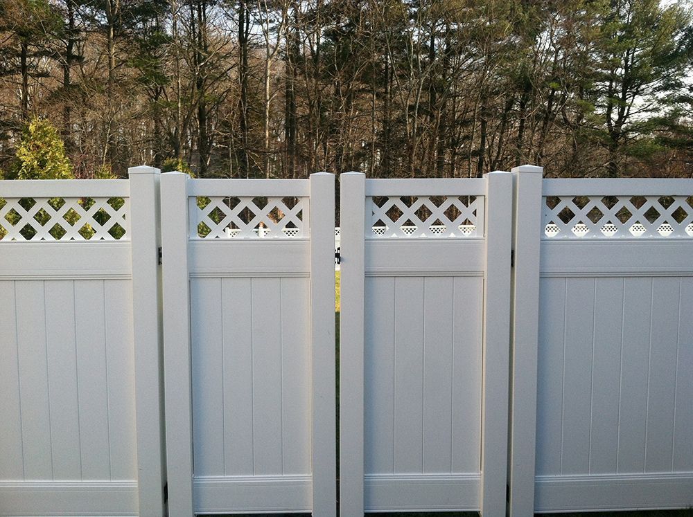 White picket fence with lattice detailing, forest background.
