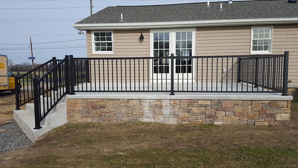 Backyard deck with black railings, stone facade, and French doors.