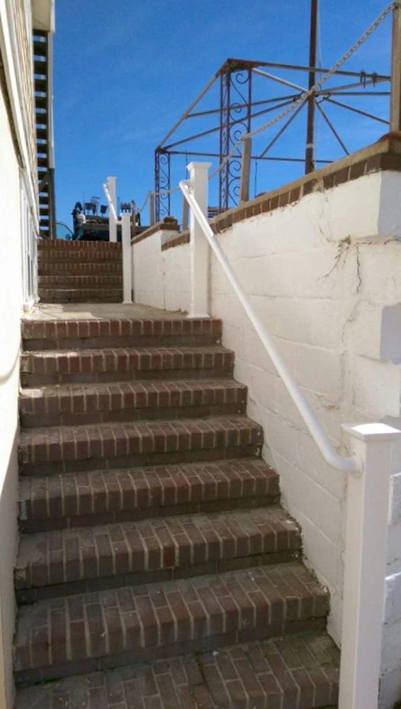 Brick staircase leading up, with white handrails and a blue sky overhead.