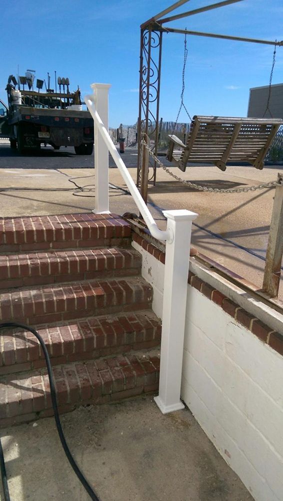 Brick steps with white railing, leading to a patio with a swing, under a blue sky.