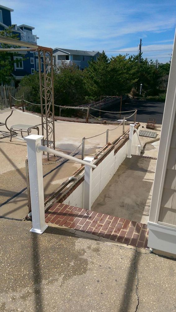 Entrance with stairs, white railings, brick steps, and a brown metal frame.