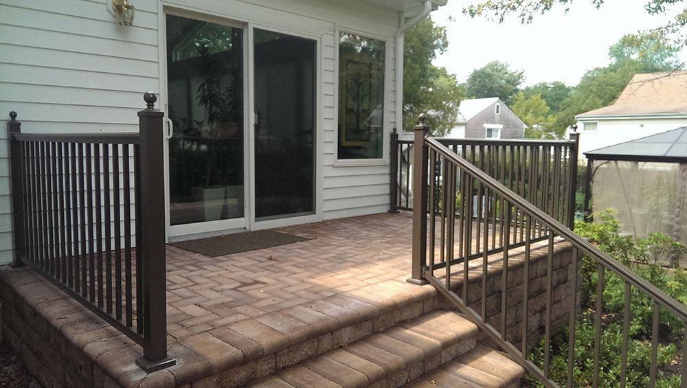 Brown brick patio with metal railing and sliding glass door.