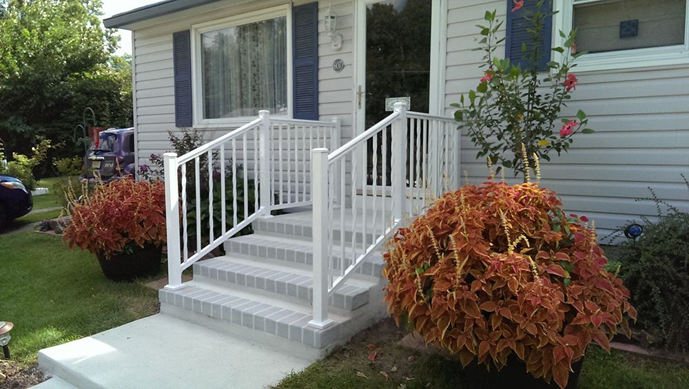White-railed steps leading to a house entrance; two red-orange potted plants flank the stairs.
