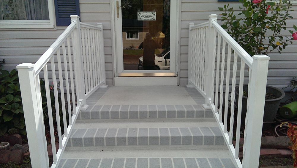 White railing and steps leading to a front door with glass.
