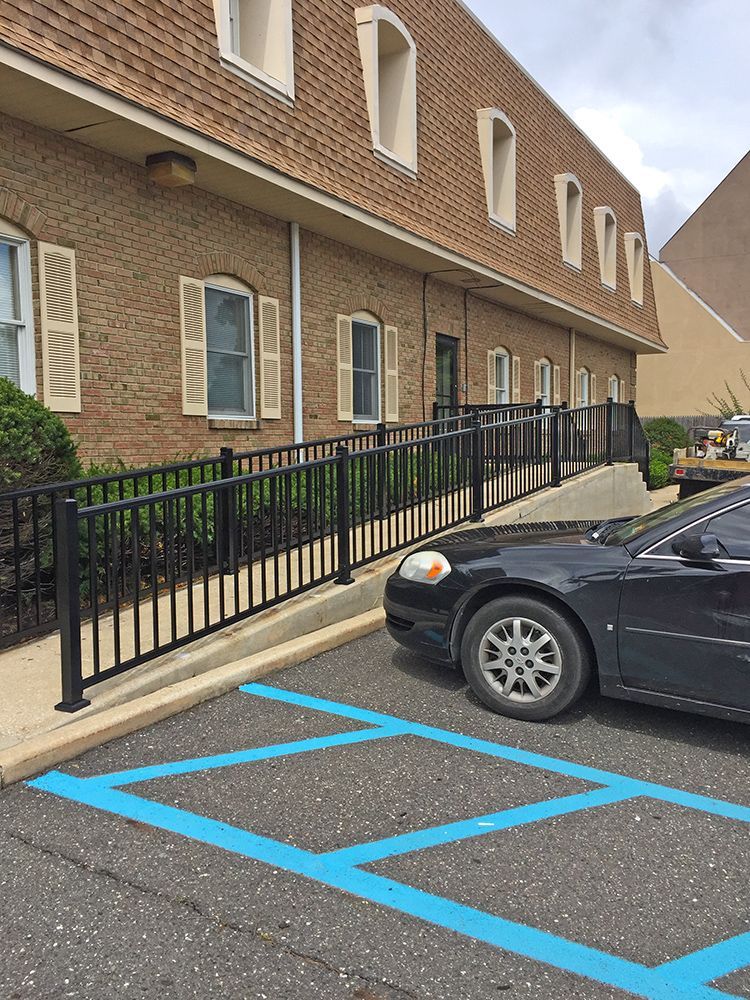 Exterior of a brick building with a wheelchair-accessible ramp and a car parked in a designated space.