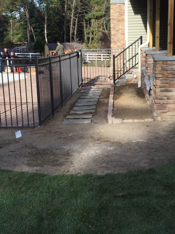 Black fence and steps leading up to a house with a person visible.