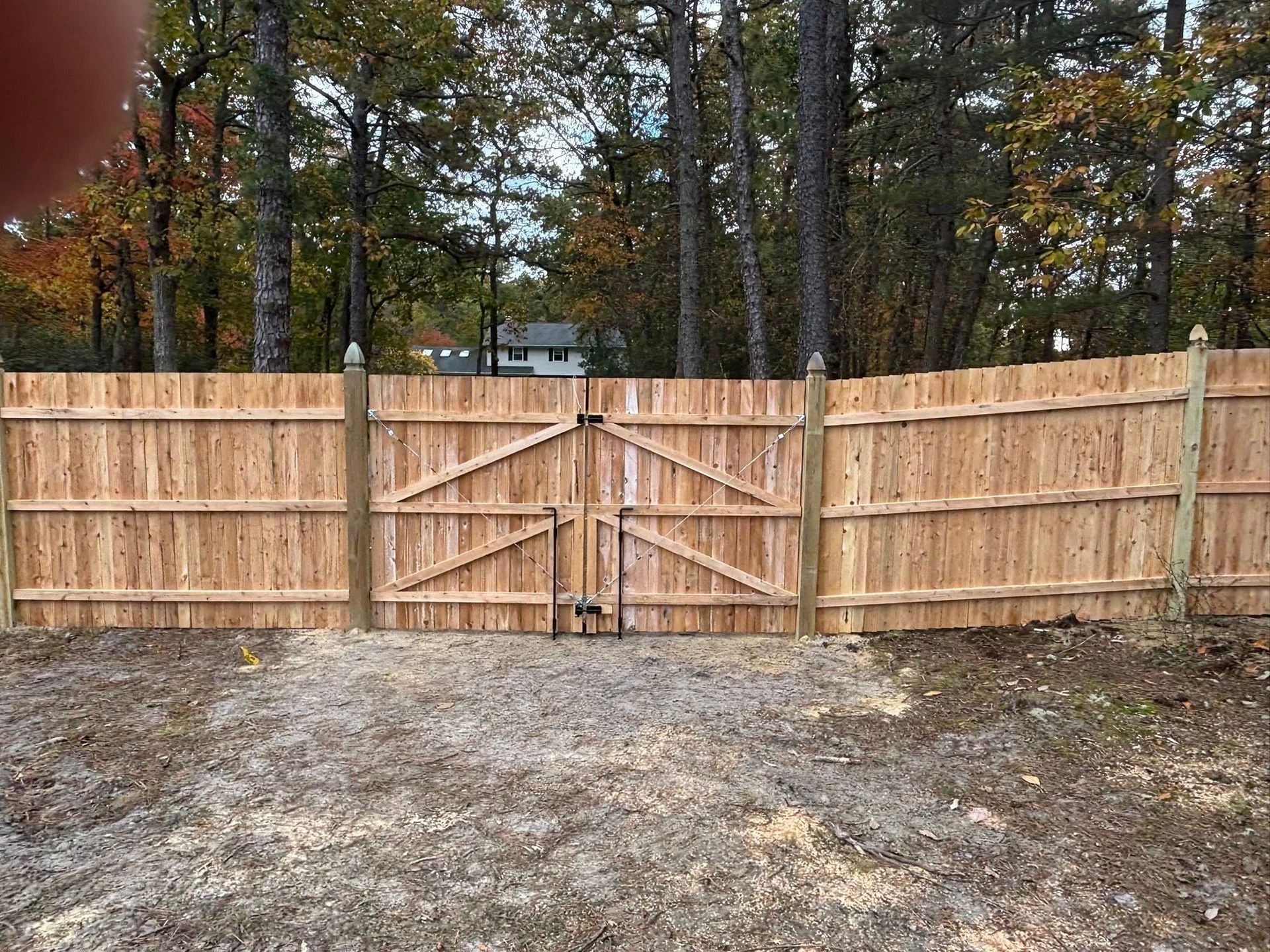 Wooden fence with gate in front of a wooded area.