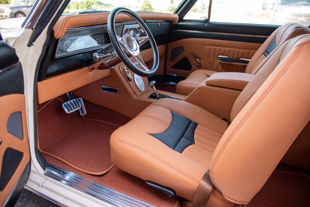 Tan and black car interior with leather seats, steering wheel, and center console.