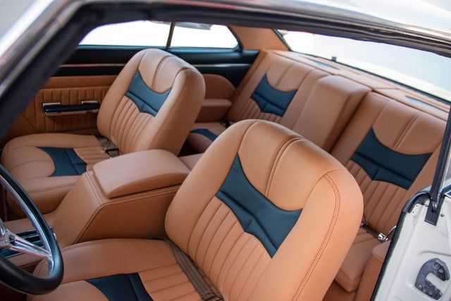 Tan car interior with black accents, a leather bench seat, and bucket seats.