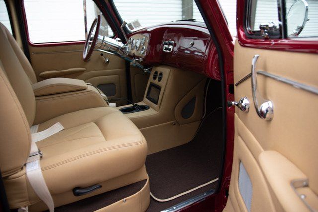 Red classic car interior with tan leather seats, custom center console, and chrome accents.
