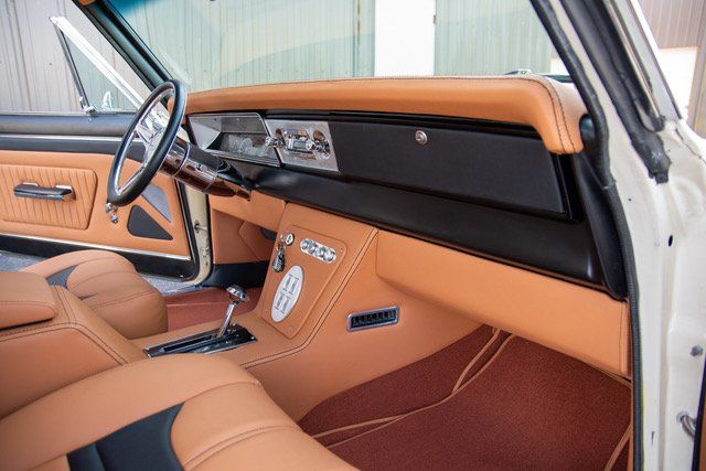 Tan and black car interior, with leather seats, wood steering wheel, and custom dashboard.