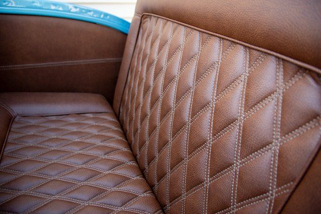Brown leather car seat with diamond stitching.